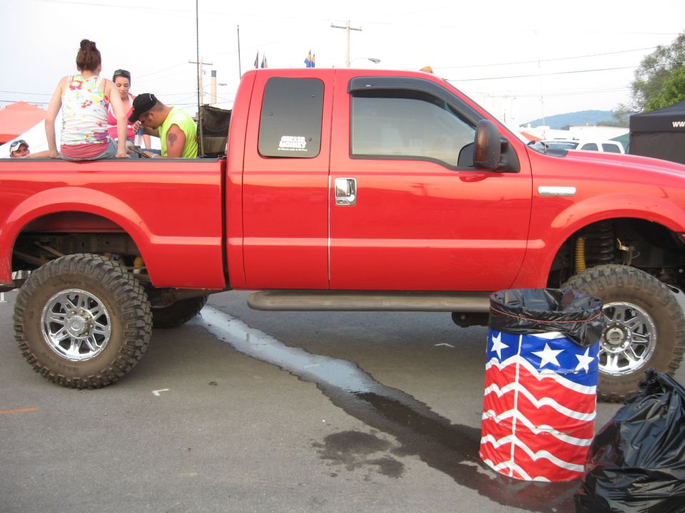 Red pickup truck side view with lifted suspension and chrome wheels