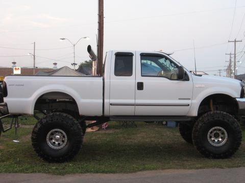 1984 Ford Bronco - White pickup truck with custom modifications, including a lift kit and large tires.