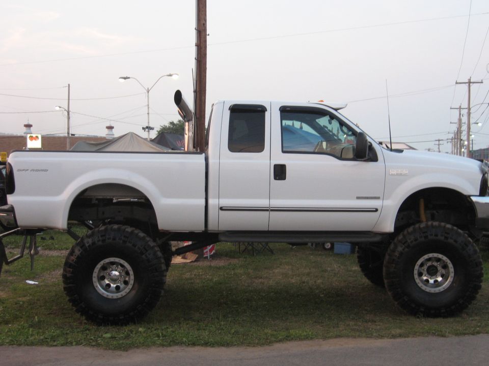 Lifted white pickup truck with large tires and a tall exhaust pipe
