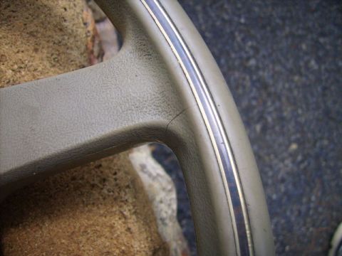 1982 Ford LTD Crown Victoria - A close-up view of a cracked tan steering wheel section with a decorative silver trim.