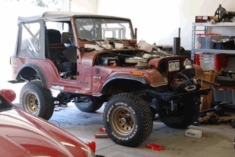 1975 Jeep CJ5 - A maroon Jeep CJ5 is shown in a garage with its hood open and front bumper removed.