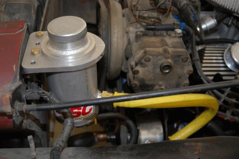 1975 Jeep CJ5 - Close-up view of engine components, including a silver canister and yellow tubing, within a vehicle's engine bay.