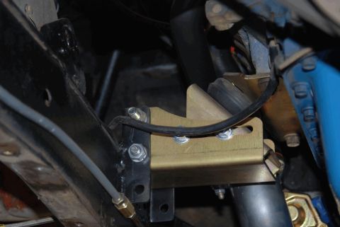 1975 Jeep CJ5 - Close-up of a gold suspension bracket mounted to a black frame, with a brake line visible.