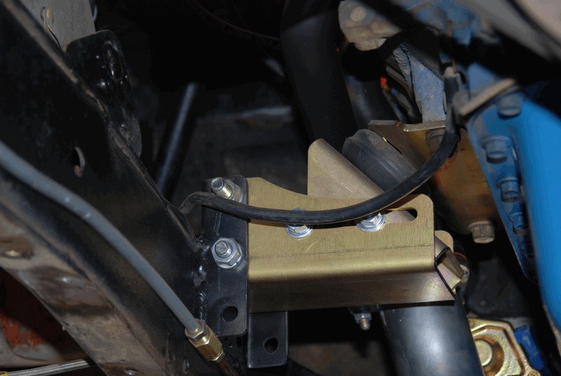 Gold suspension bracket bolted to black frame with brake line attached