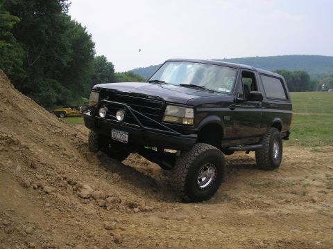 1995 Ford Bronco - A black Ford Bronco navigates a steep dirt incline, its off-road capabilities.