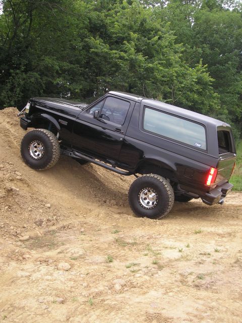1995 Ford Bronco - A black Ford Bronco navigates a steep dirt incline, its off-road capabilities.