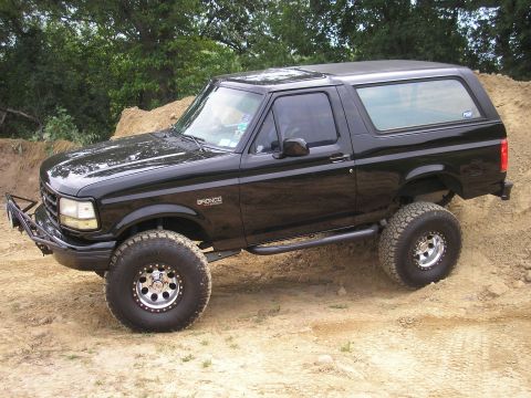 1995 Ford Bronco - This black 1995 Ford Bronco is shown off-roading with its large tires and lifted suspension.