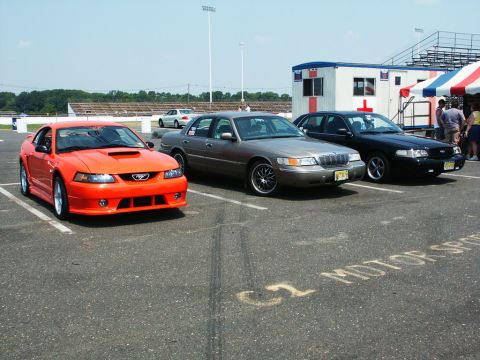 2001 Mercury Grand Marquis - Three cars are parked at the 6th Annual CJMF Car/Truck Show, including a Mustang and two sedans.