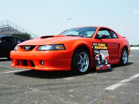 2001 Mercury Grand Marquis - An orange 2004 Ford Mustang is displayed at a car show next to a black vehicle.