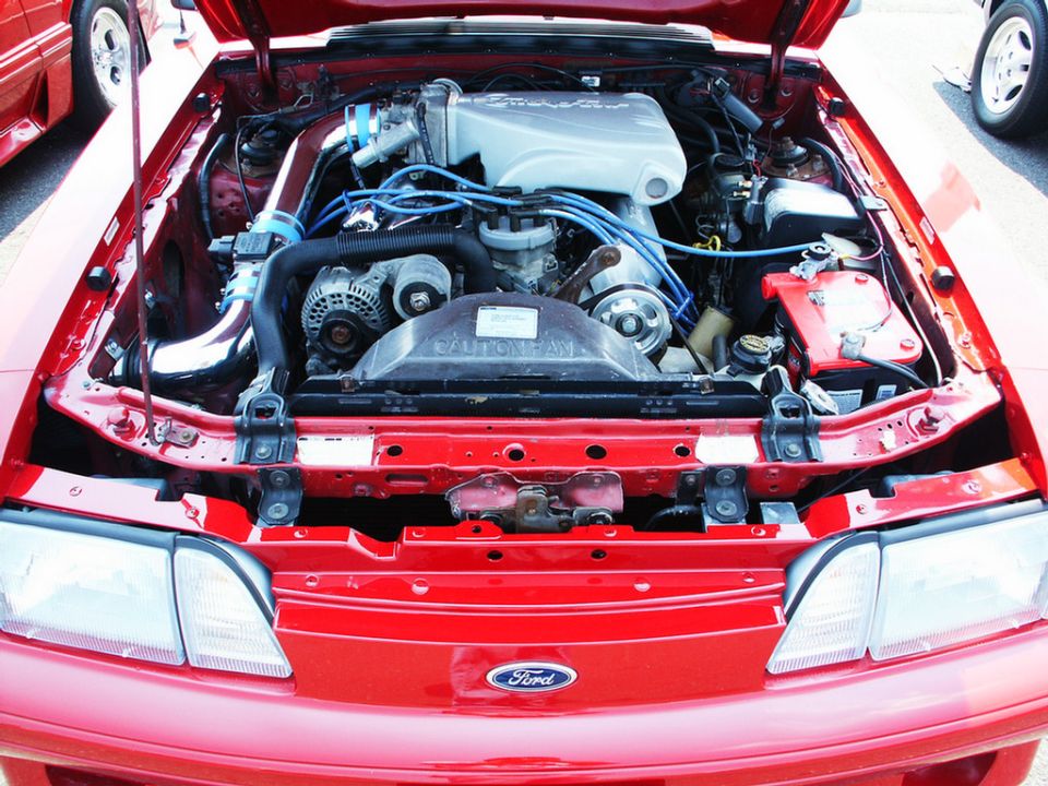 Red Ford Mustang engine bay with chrome intake and blue spark plug wires