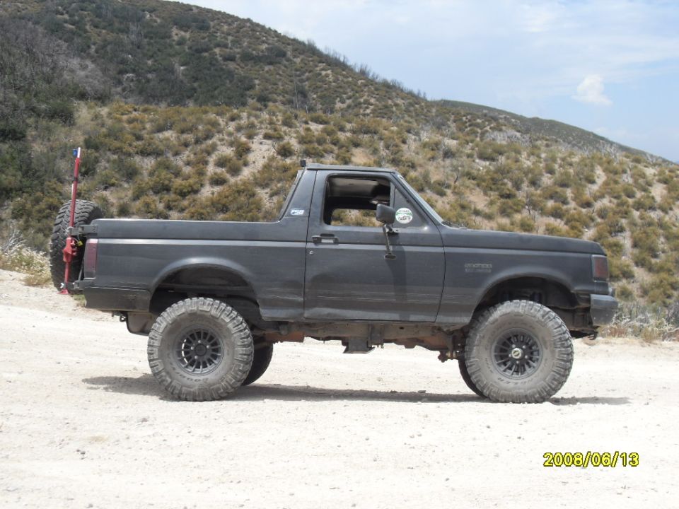 Dark gray Ford Bronco, third generation, side view, lifted suspension, off-road tires, spare tire carrier on rear