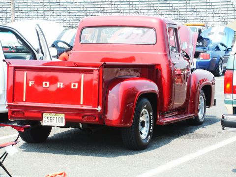 2001 Mercury Grand Marquis - A red 1956 Ford F-100 pickup truck is seen from the rear at a car show with other vehicles present.