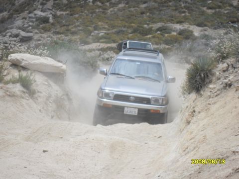 1990 Ford Bronco - A silver Toyota 4Runner navigates a dusty off-road trail with another vehicle behind it.