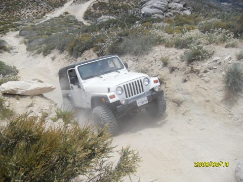 1990 Ford Bronco - A white Jeep Wrangler navigates a dusty off-road trail.
