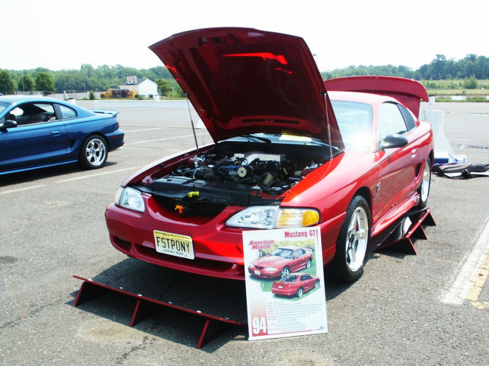 Red 1994 Mustang GT with hood open, parked next to a blue Mustang