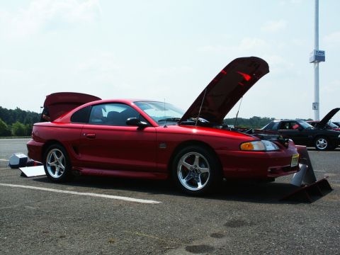 2001 Mercury Grand Marquis - A red coupe with its hood and trunk open sits on asphalt at an outdoor car show.