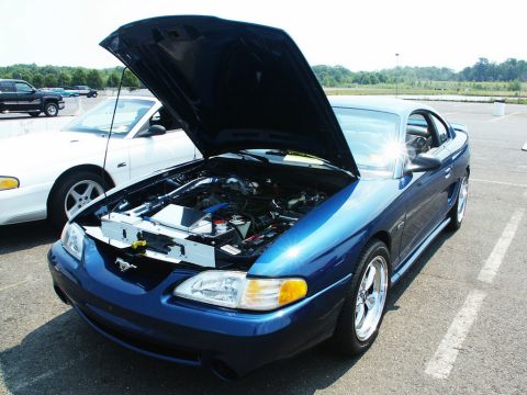 2001 Mercury Grand Marquis - A blue Ford Mustang is displayed with its hood open, revealing the engine compartment and chrome wheels.
