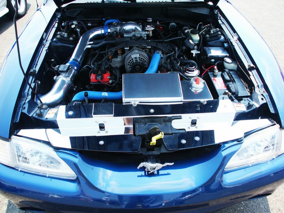 Blue Ford Mustang engine bay with aftermarket intake and chrome accents