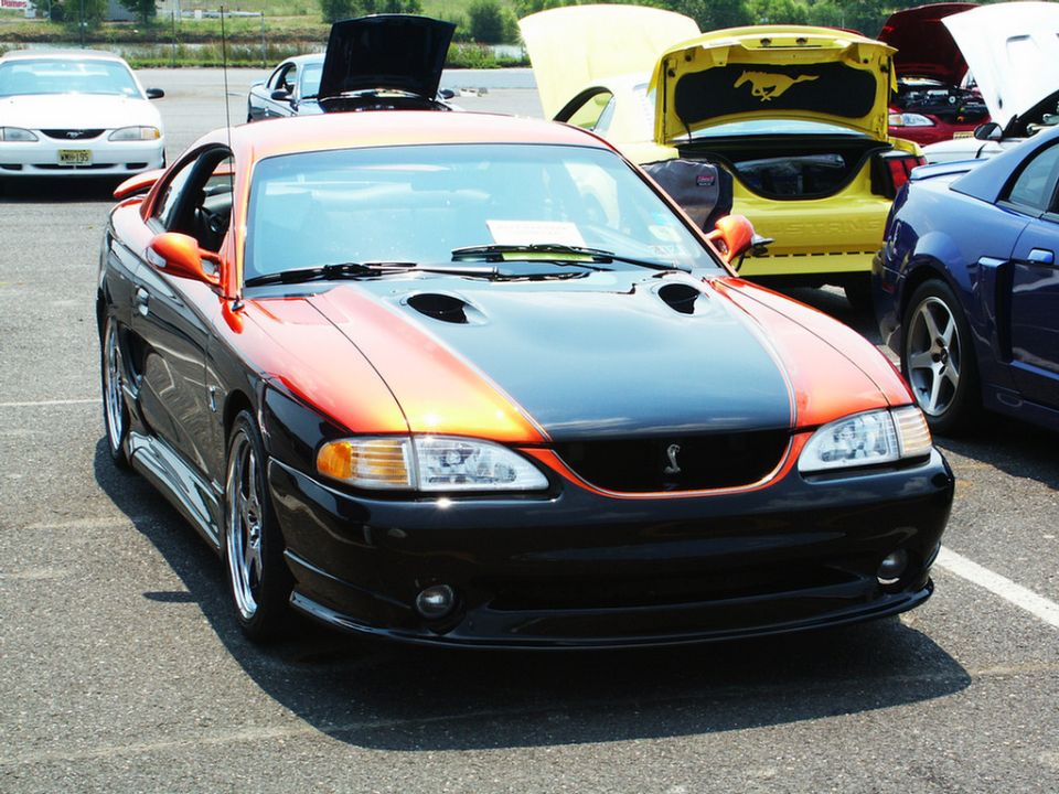 Front view of a two-tone orange and black 1996 Ford Mustang Cobra with hood scoops