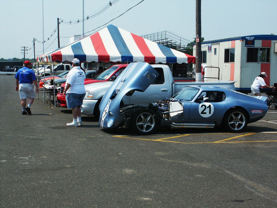 Blue race car with number 21 on door, hood open, parked at car show