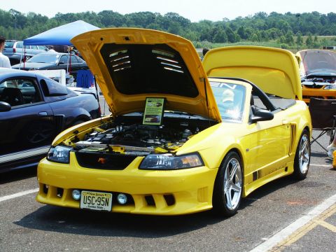 2001 Mercury Grand Marquis - A yellow convertible sports car is displayed with its hood open at a car show.