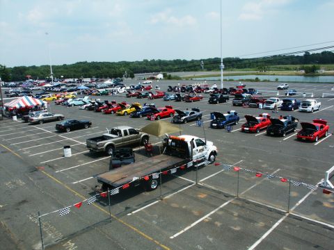 2001 Mercury Grand Marquis - A large gathering of vehicles is displayed in an outdoor parking lot under a partly cloudy sky.