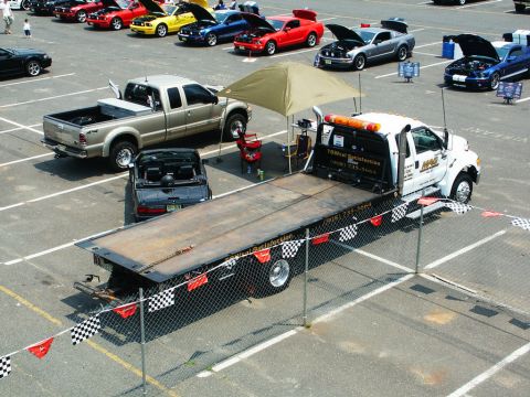 2001 Mercury Grand Marquis - A tow truck transports a black convertible at a car show, with several other vehicles visible in the background.