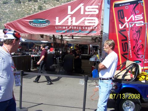 1972 Ford Ranchero - A man stands by a blue golf cart at an event with a large red banner overhead displaying 'Vis Viva'.