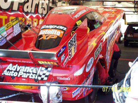 1972 Ford Ranchero - A red drag racing car is seen from the rear, covered in sponsor decals.