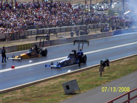 1972 Ford Ranchero - Drag racing cars compete on a track with spectators filling the grandstands.