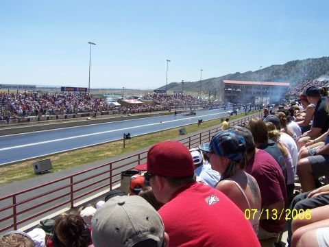1972 Ford Ranchero - A drag racing event is underway with a large crowd in the stands under a clear blue sky.