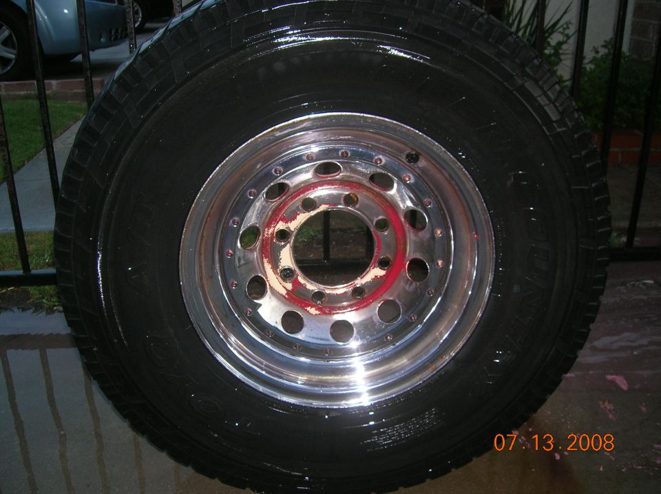 Tire mounted on a chrome rim with red accents, wet surface