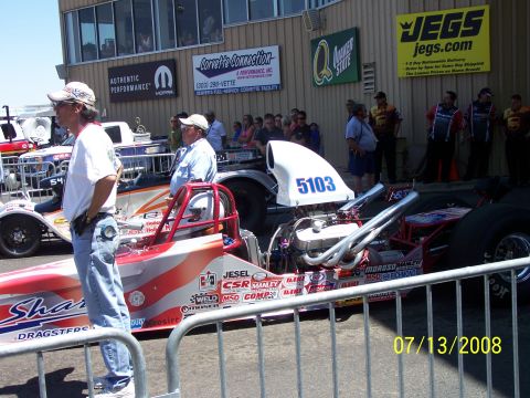 1972 Ford Ranchero - A dragster is parked at an event with spectators and sponsor banners in the background.