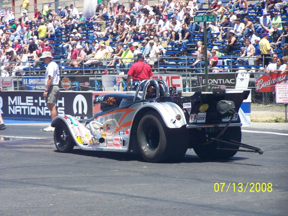 Drag racing car with large rear tires and spoiler, parked on a track with spectators in the background. Date stamp reads 07/13/2008