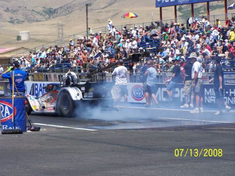 1972 Ford Ranchero - A drag racing car performs a burnout on the track, creating smoke, with a crowd watching from the stands.