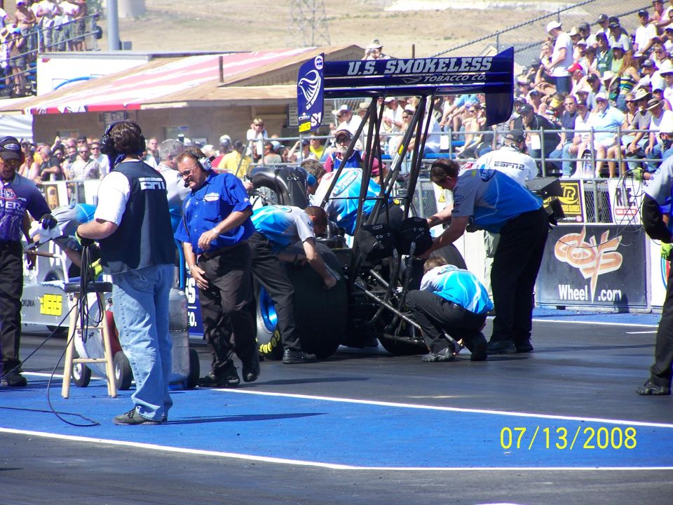 Drag racing car with crew working on the rear wheel and engine