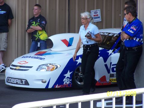 1972 Ford Ranchero - A white drag racing car with a distinctive aerodynamic hood is parked, with people standing nearby.