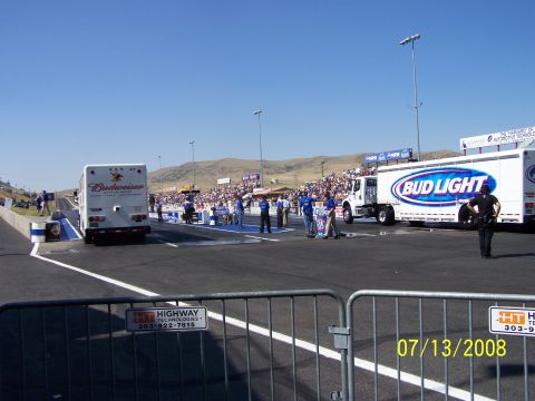 1972 Ford Ranchero - A drag strip scene with Budweiser and Bud Light trucks under a clear blue sky.