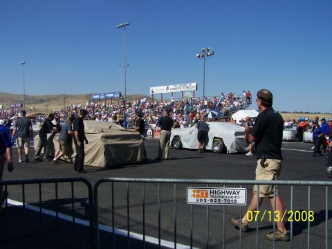 1972 Ford Ranchero - Cars are being moved at a drag strip event, with a large crowd watching from the stands.