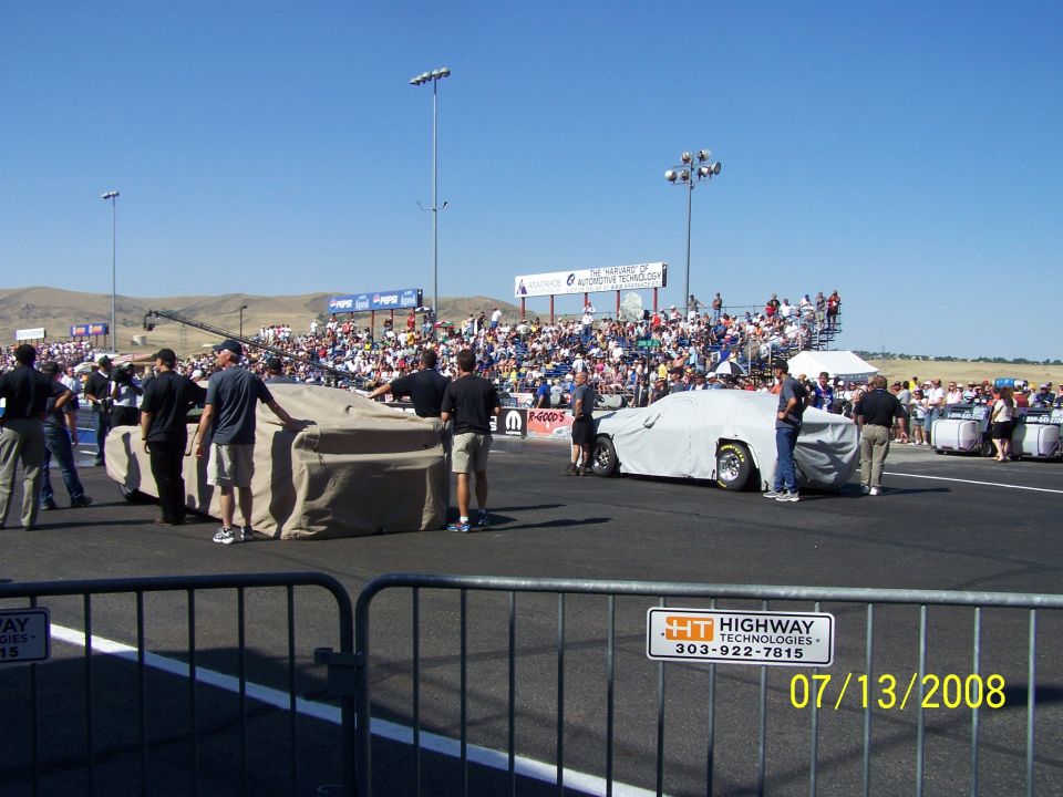 Drag strip with covered vehicles and spectators in the stands. Date stamp reads 07/13/2008