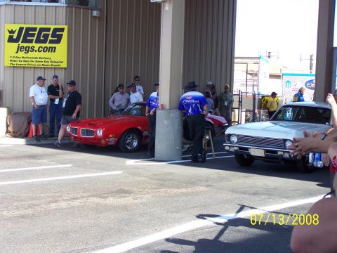 1972 Ford Ranchero - A red muscle car is parked next to a white car, with a JEGS sign visible on the building.
