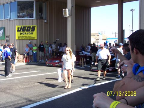 1972 Ford Ranchero - A sunny day at the drag strip with spectators and race cars, a JEGS banner on the building.