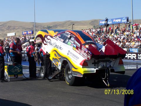 1972 Ford Ranchero - A drag racing car is prepared on the track with a large crowd in the background.
