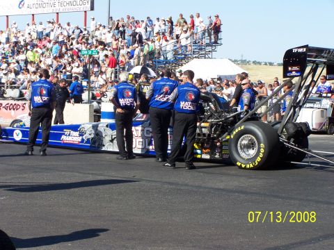 1972 Ford Ranchero - A drag racing car and its crew are on the track with spectators in the stands.