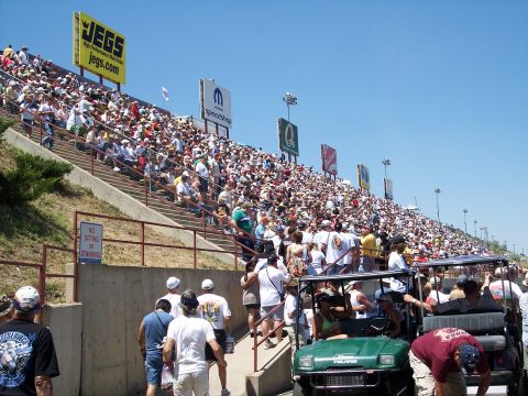 1972 Ford Ranchero - A large crowd watches an event from tiered seating at a speedway, with sponsor signage overhead.