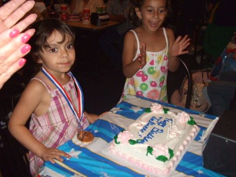 2008 Jeep Cherokee - Two young girls celebrate a birthday with a cake, one wearing a medal and the other clapping.