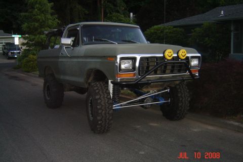 1978 Ford Bronco - A modified 1978 Ford Bronco sits on a street, its lifted suspension and large tires prominent.