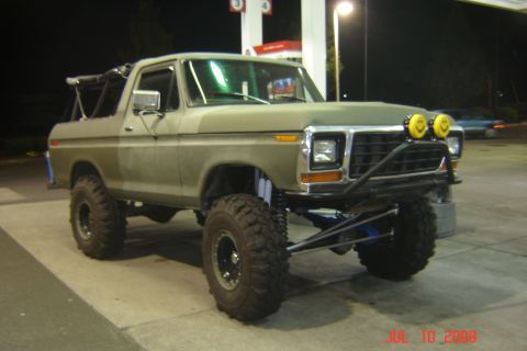 1978 Ford Bronco - This modified Ford Bronco is parked at a gas station, large off-road tires and a custom front bumper with unique lighting.