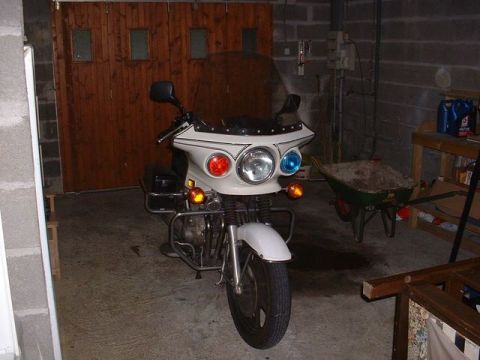 1991 Ford Crown Victoria - A white police motorcycle with a large windshield and emergency lights is parked indoors.