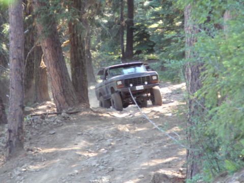 1991 Ford Bronco - This truck is navigating a steep, wooded trail with a tow rope attached.